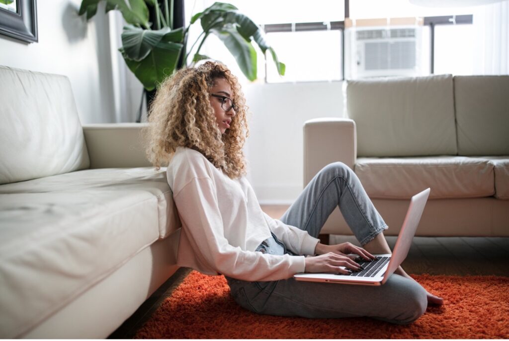 A woman working on her laptop at home represents the wellness home trends we expect to see in the future
