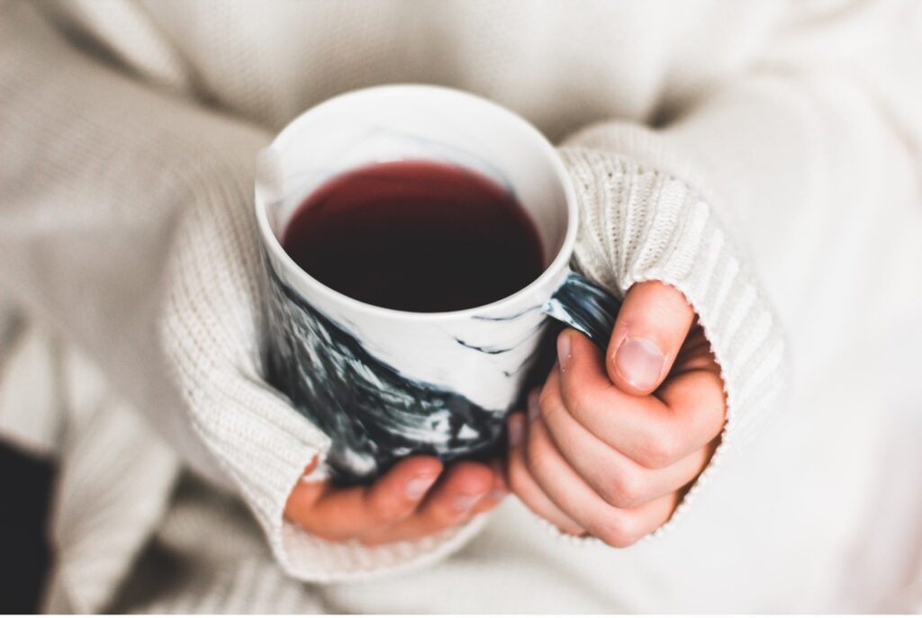 Close up of hands holding a warm cup of tea represents the thermal comfort concept