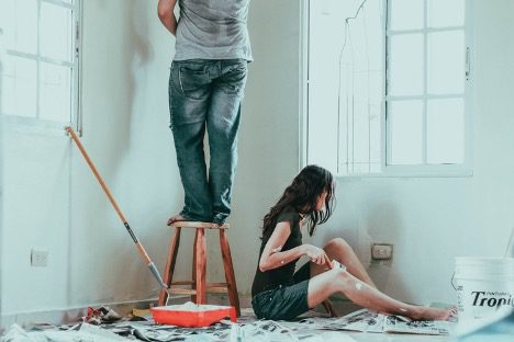 A man and woman painting the walls of a room represents the WELL materials concept