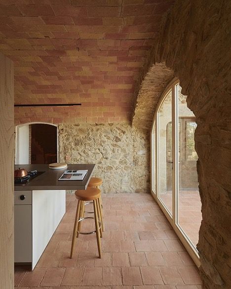 A rustic kitchen with stone walls and terra cotta tile ceiling and floor represents the WELL Building Standard