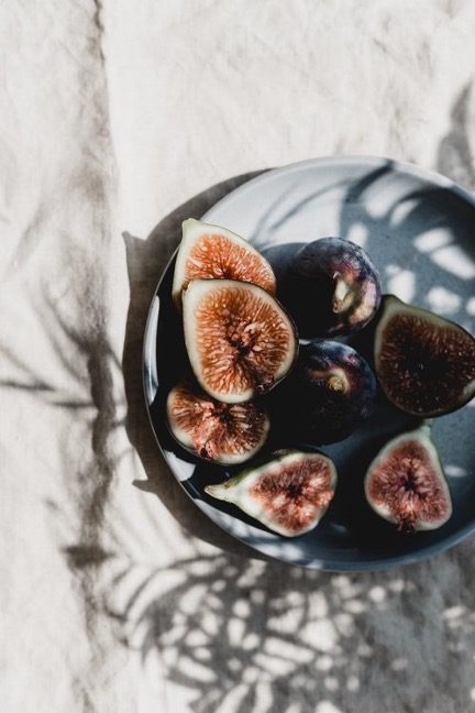 A bowl of fresh figs cut in half and arranged on top of a linen tablecloth represents the WELL nourishment concept