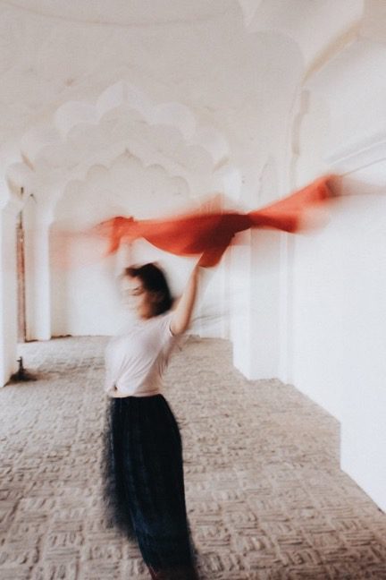Woman dancing with red scarf in a Moroccan building represents the WELL movement concept