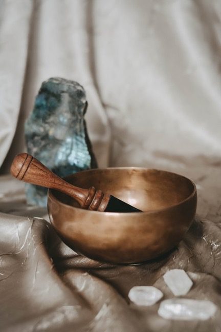 Tibetan meditation bowl beside a large piece of labradorite and several pieces of quartz crystal represents the WELL mind concept