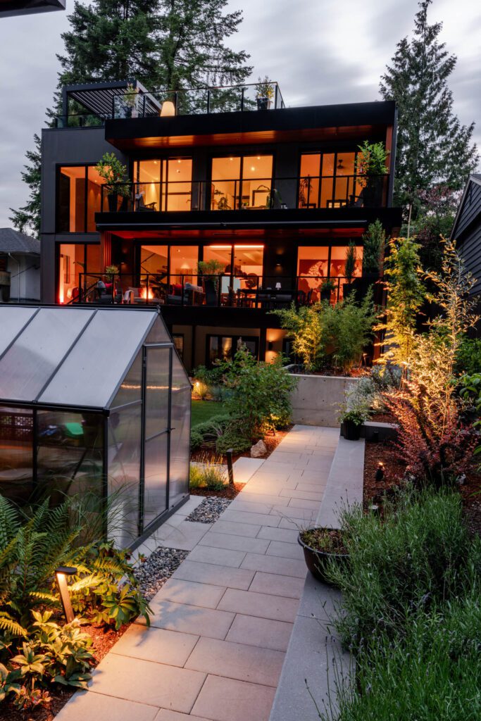 The backyard features stunning landscaping, a glasshouse, and a walkway to the garage.