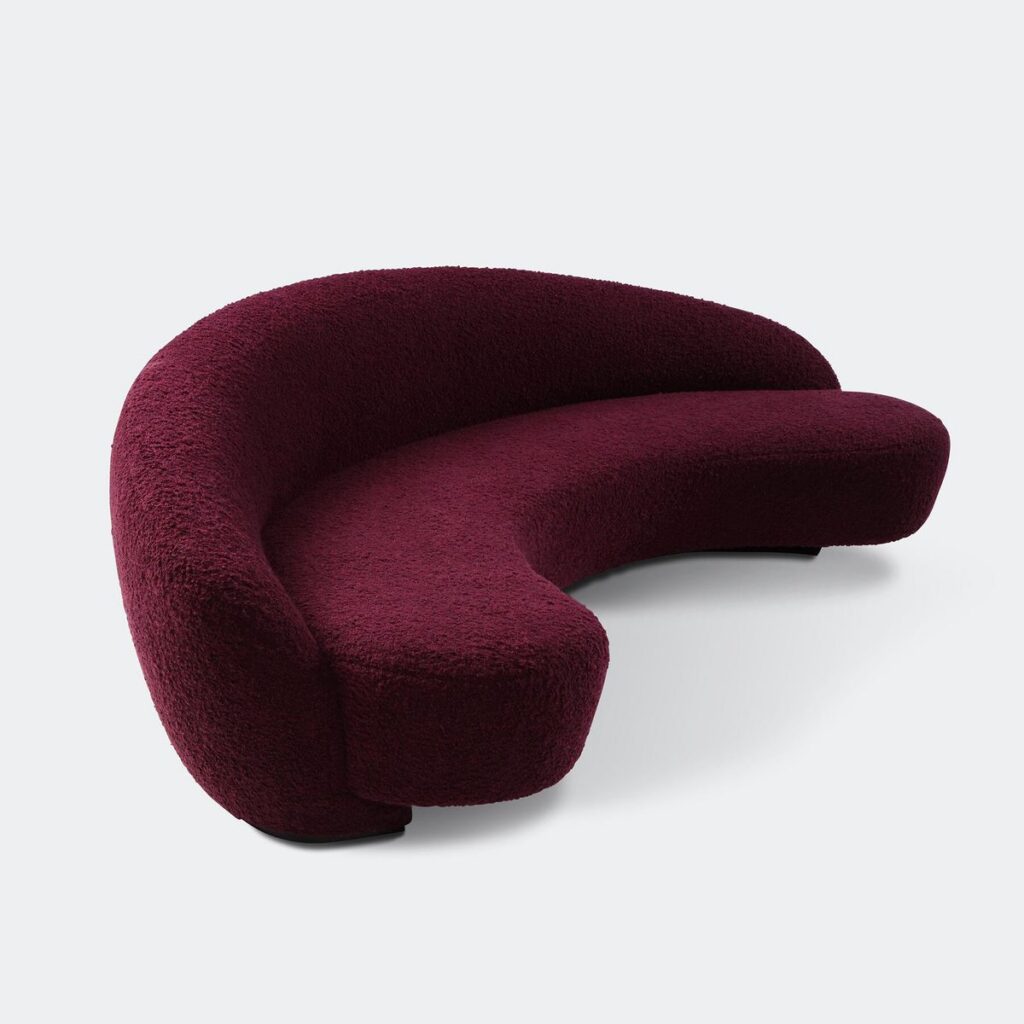 Dramatic curved sofa in oxblood boucle